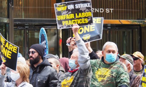 Man holding unfair labor practices sign.